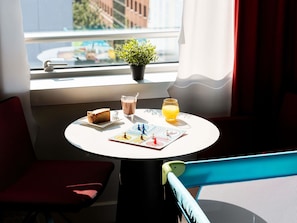 A table with a slice of cake, a glass of milk, a glass of orange juice, and a small potted plant. - Mercure Paris La Défense Grande Arche (Nanterre)