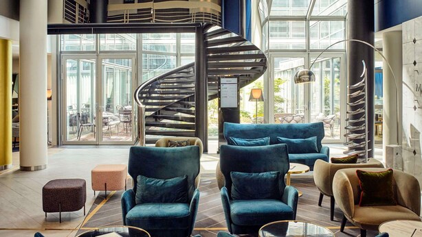 Un hall d’entrée moderne avec un escalier en colimaçon, des sièges confortables et de grandes fenêtres.
