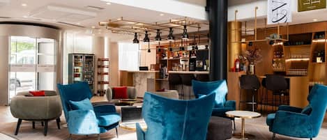 A modern lobby with seating areas, a bar, and a reception desk.