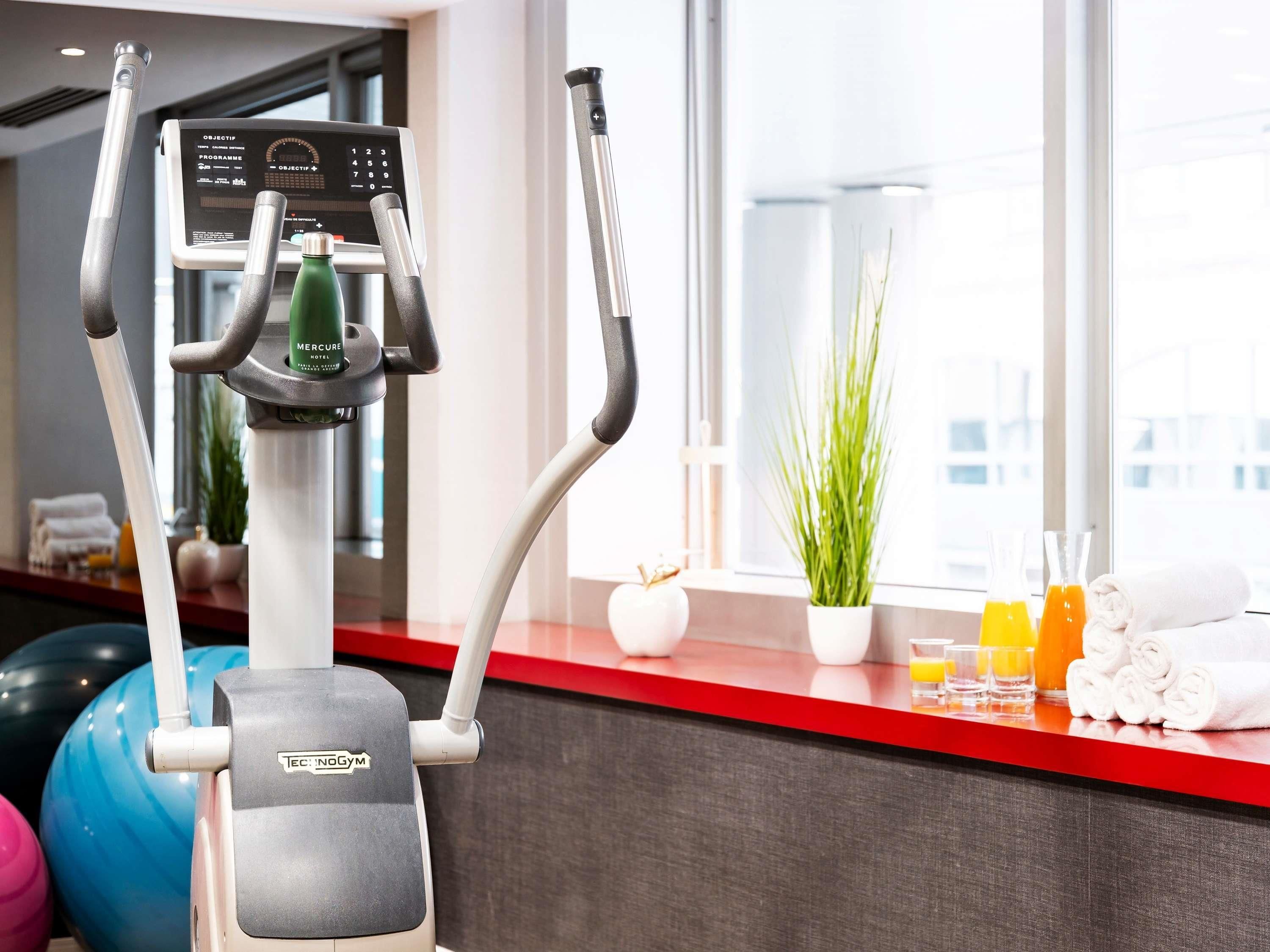 An exercise machine, a window with a view, and a counter with towels and drinks.