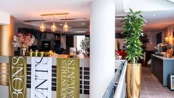 Een moderne hotel lobby met een receptiebalie, een grote kamerplant en een spandoek met de naam van het hotel.