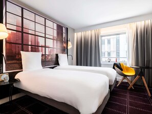 A hotel room with two beds, a desk with a chair, a window with curtains, and a cityscape view. - Mercure Paris La Défense Grande Arche (Nanterre)
