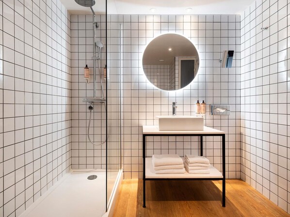 Un baño moderno con ducha, lavamanos, espejo y toallero.