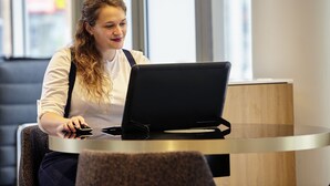 A person sitting at a round table with a laptop and a smartphone. - Mercure Paris La Défense Grande Arche (Nanterre)
