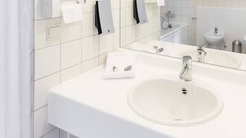 Un baño moderno con un lavamanos blanco, un espejo y dispensadores de toallas.