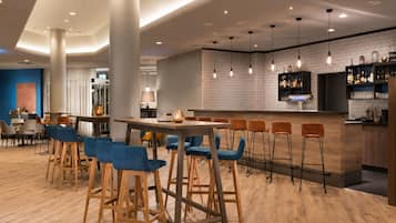 Un área de bar moderna con taburetes de madera, barra y lámparas colgantes.