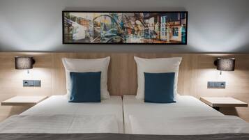 Een tweepersoonsbed met witte en blauwe kussens, een houten hoofdbord en een groot abstract schilderij erboven.