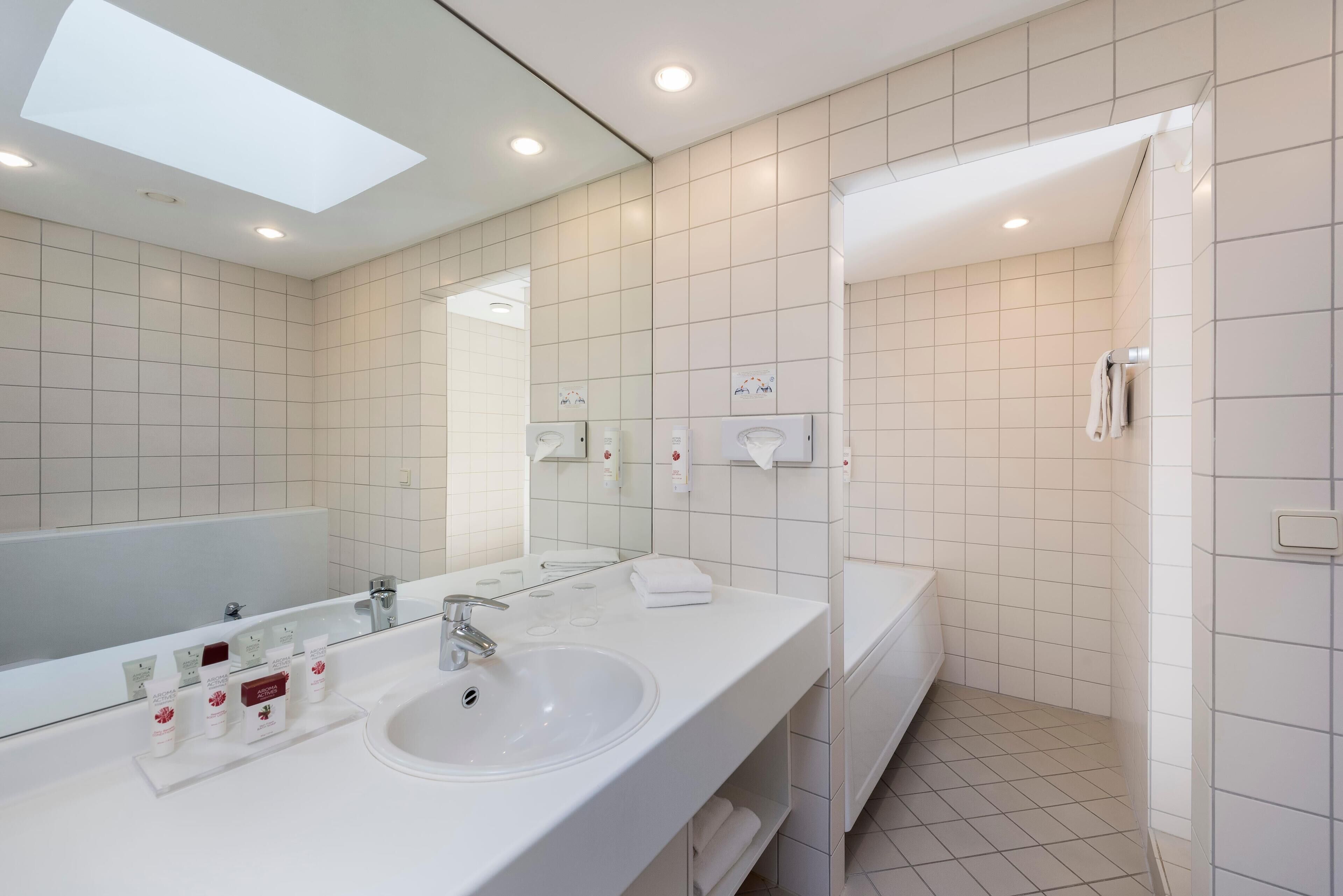 A modern bathroom with a large mirror, a sink, and a shower area.
