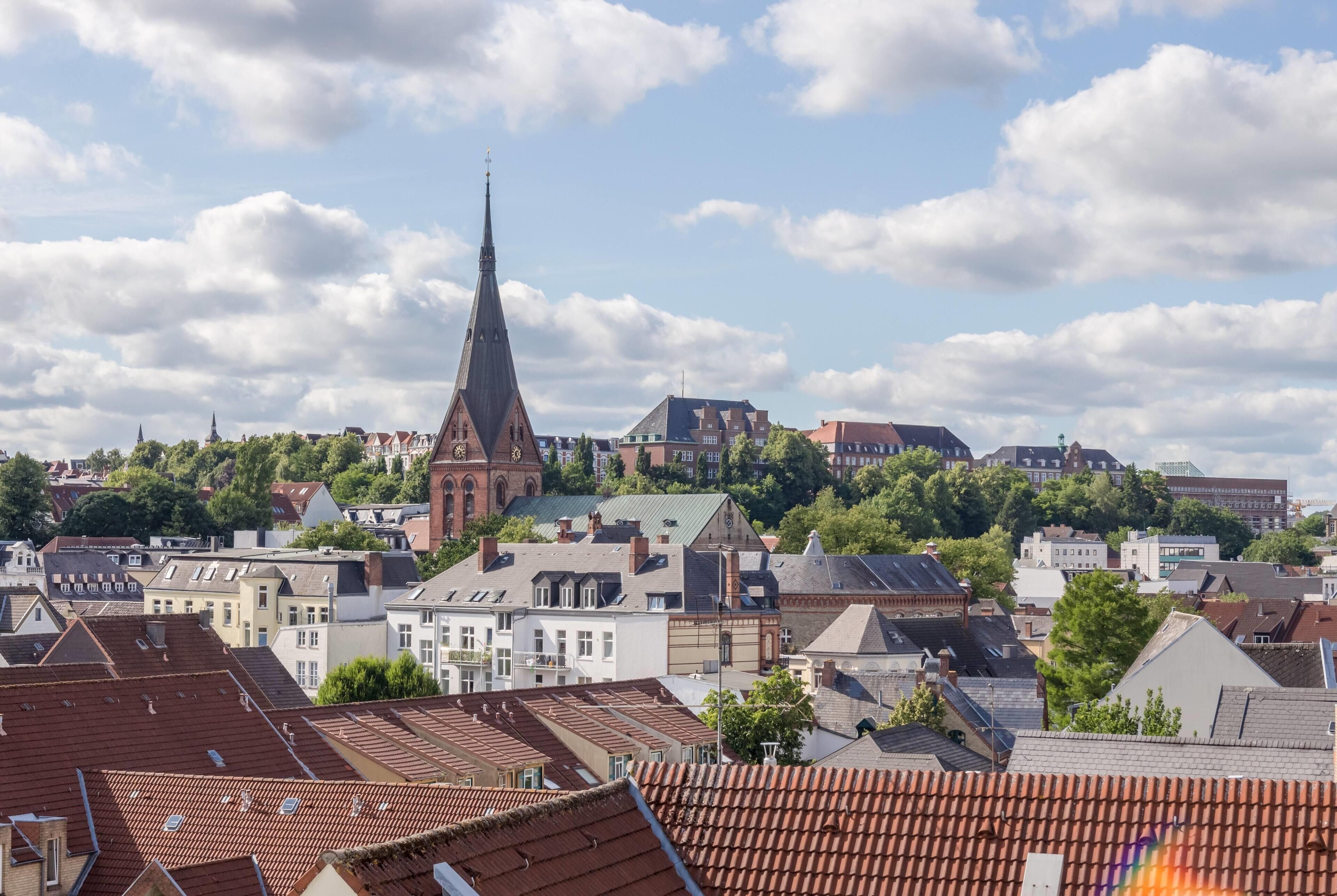 A cityscape with a prominent church steeple, residential buildings, and a mix of modern and traditional architecture.