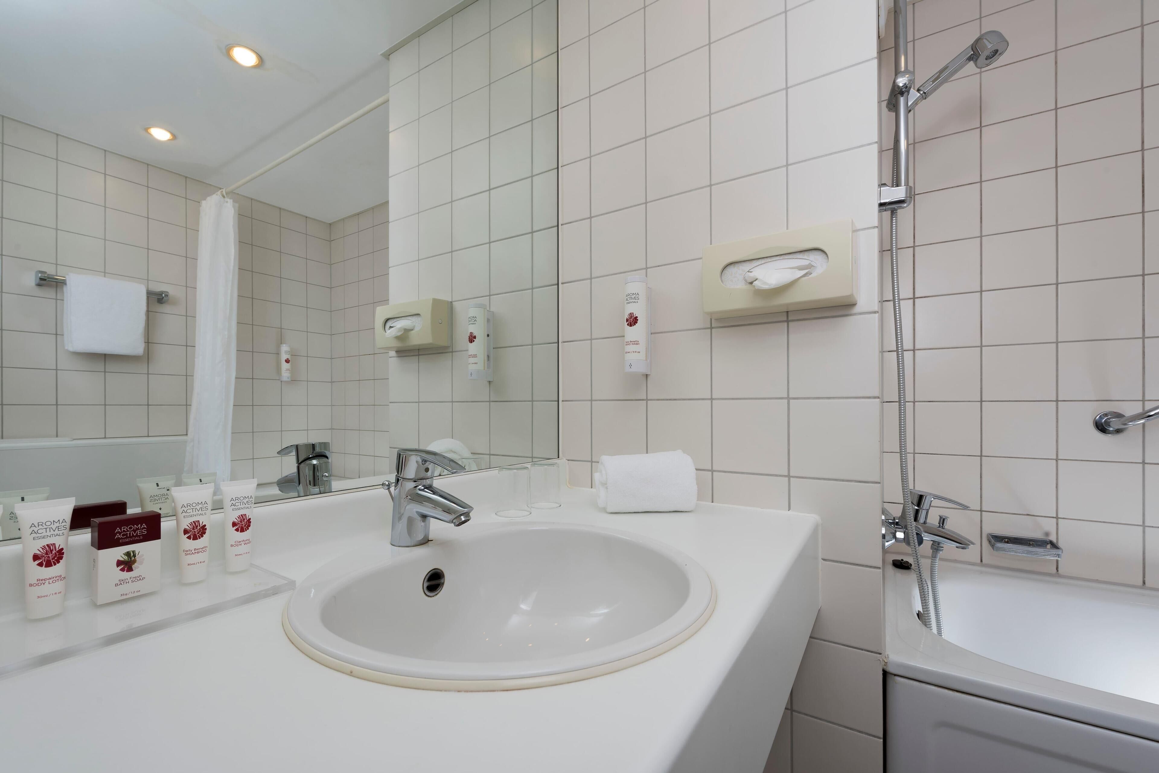 Un baño moderno con lavamanos, espejo y ducha blancos.
