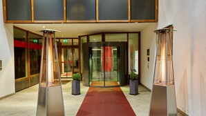 Ein Hotel mit Eingangsbereich, einem roten Teppich, zwei Standheizungen und einer Drehtür.