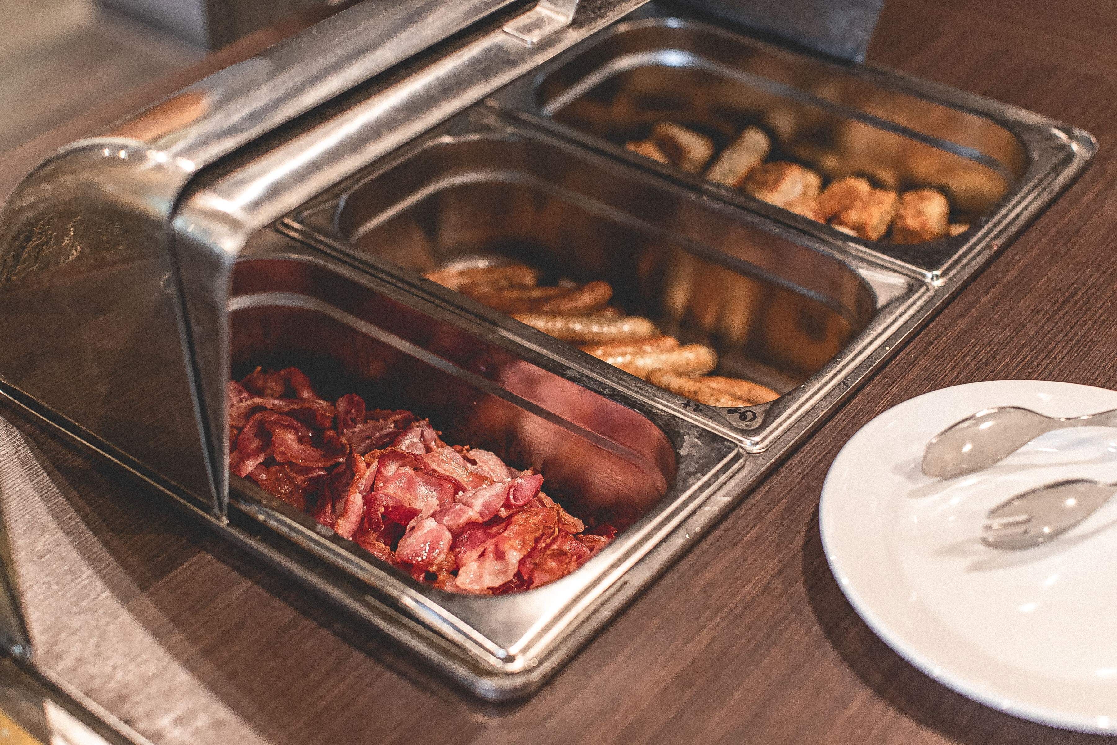 A buffet with various food options including bacon and sausages.