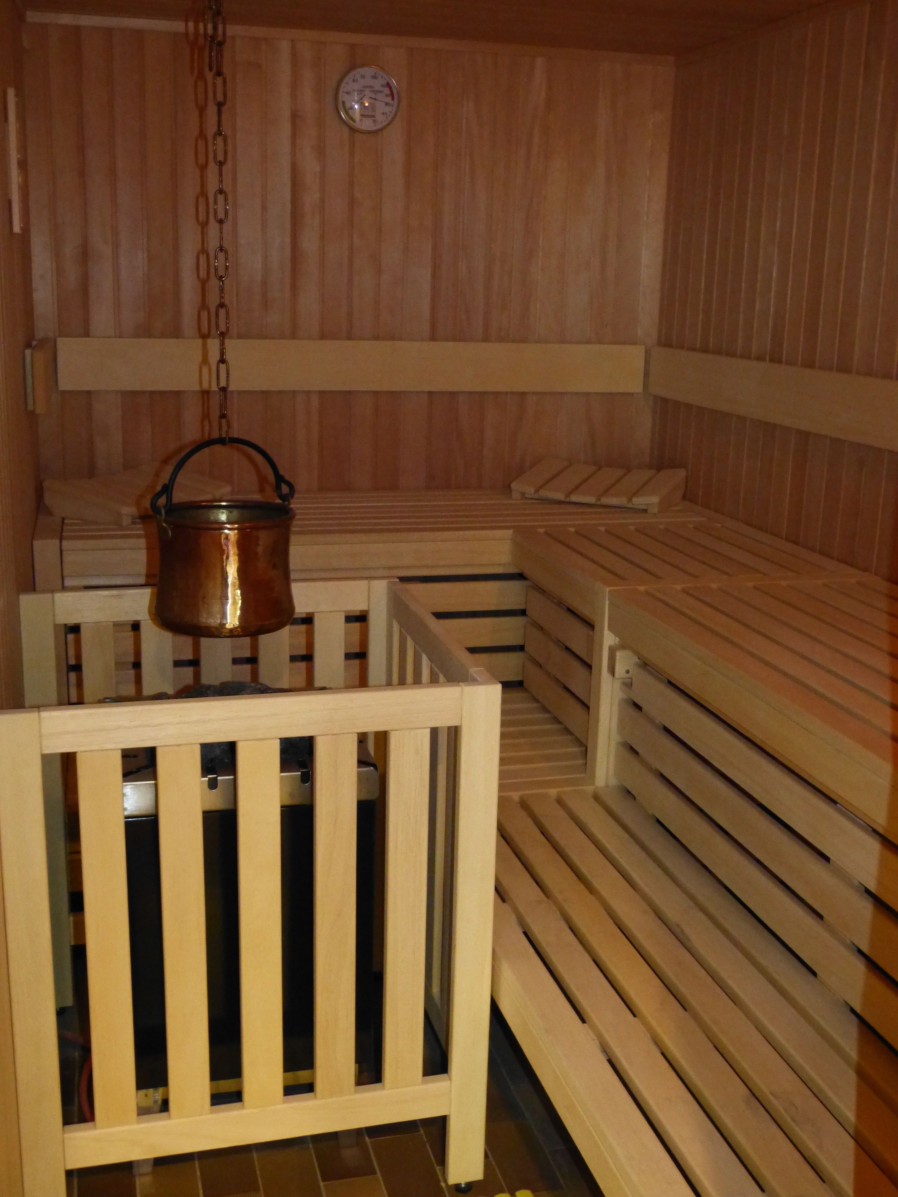 Una sauna con panche in legno e una pentola di rame appesa.