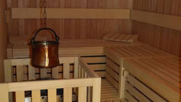 Una sauna con panche in legno e una pentola di rame appesa.