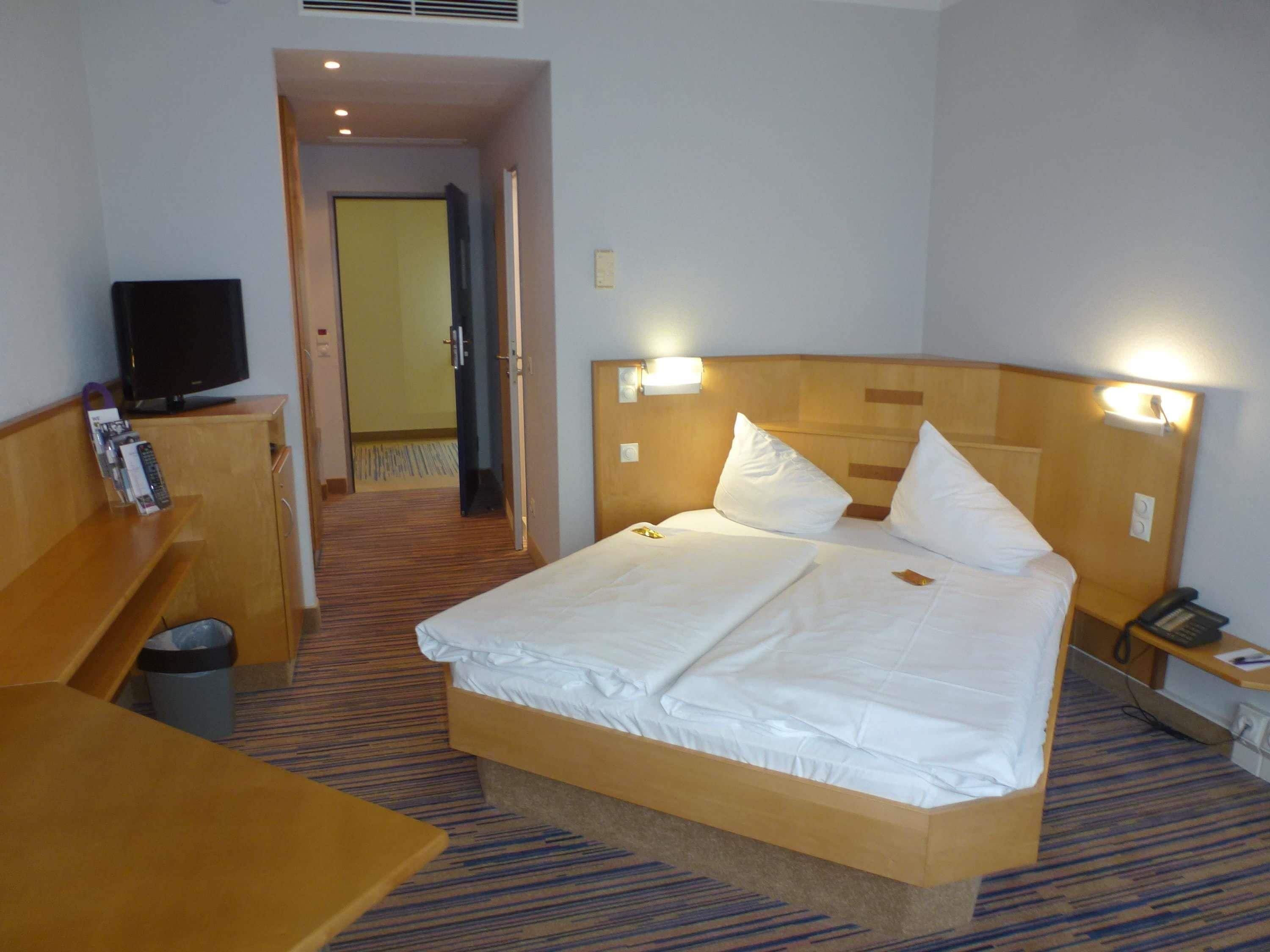 Ein Hotelzimmer mit Bett, Nachttisch, Fernseher und Mülleimer.