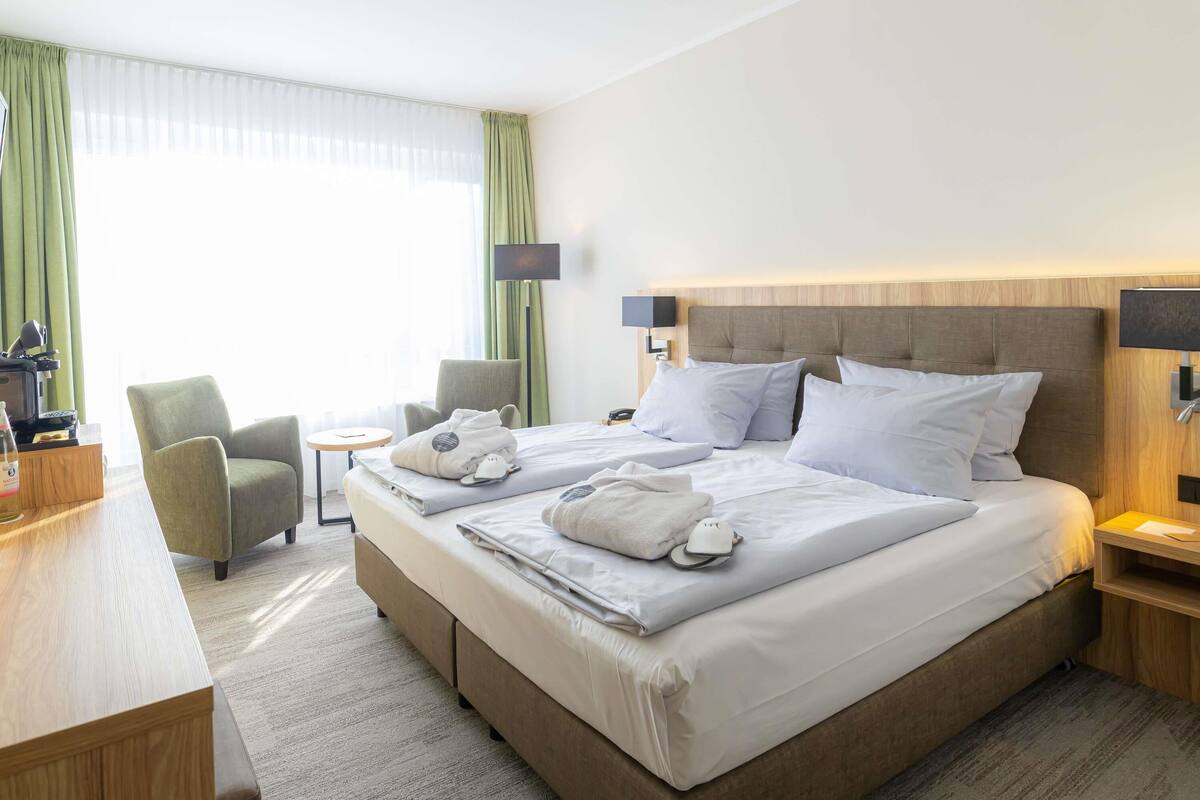 Ein Hotelzimmer mit einem großen Bett, einem Schreibtisch, einem Stuhl, einem kleinen Tisch und einer Lampe.