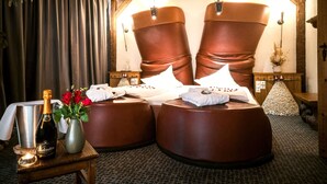 A room with a large bed, a bedside table with a bottle and flowers, and a hanging plant. - Mercure Hotel Riesa Dresden Elbland (Riesa)