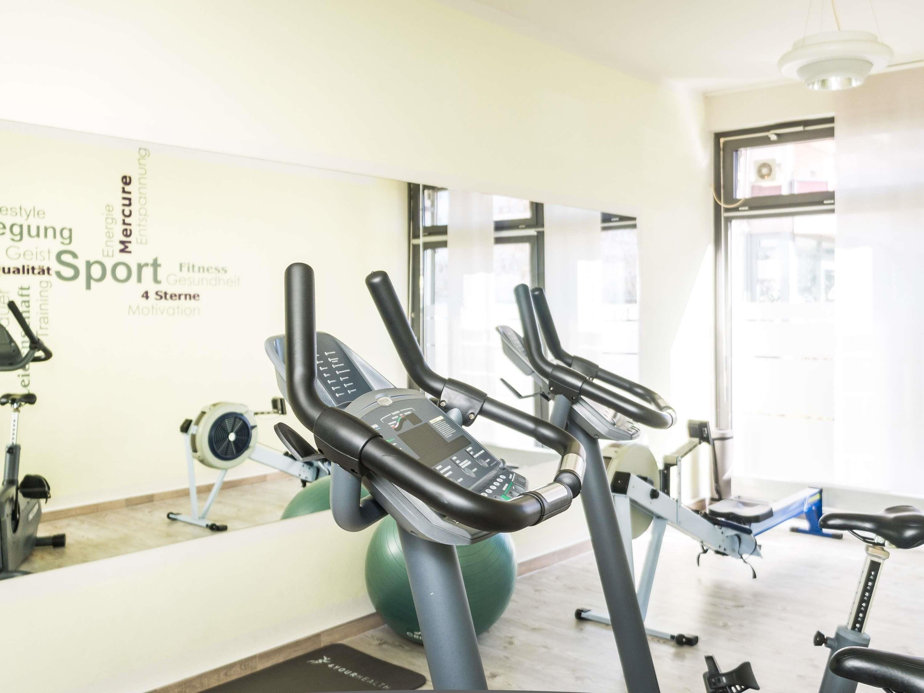 A gym with three stationary bikes, a green exercise ball, and a wall with motivational words.