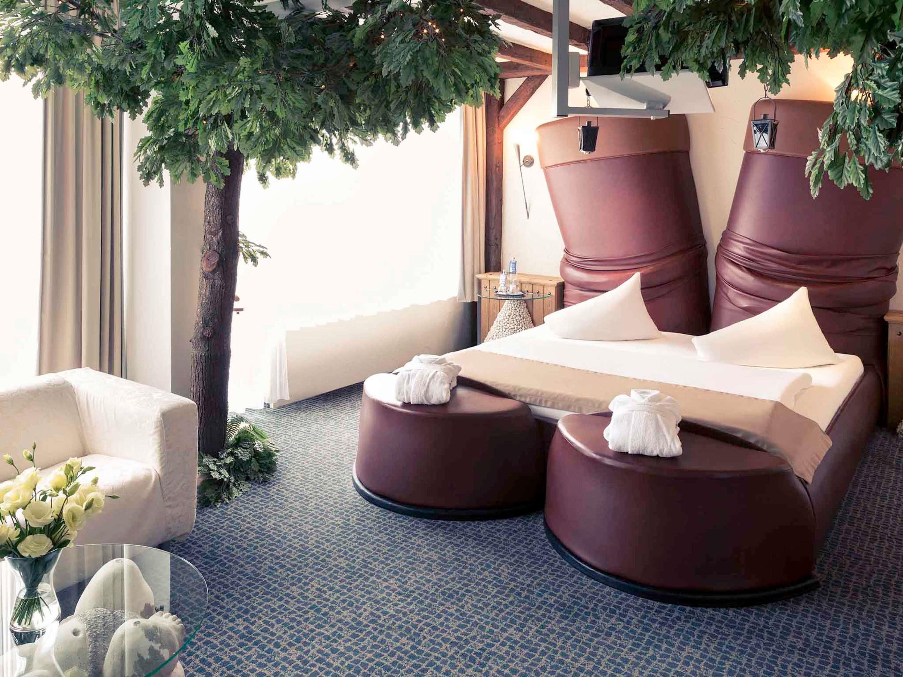 Una habitación con sillón de masaje, sofá y una mesita con un jarrón de flores.
