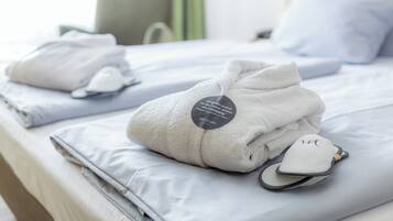 Una cama bien hecha con toallas dobladas, pantuflas, una almohada y una etiqueta que indica una marca.