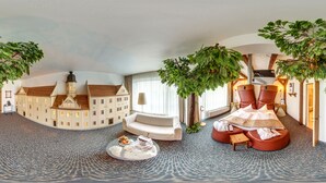 A luxurious room with a round table, a sofa, and a large tree. - Mercure Hotel Riesa Dresden Elbland (Riesa)