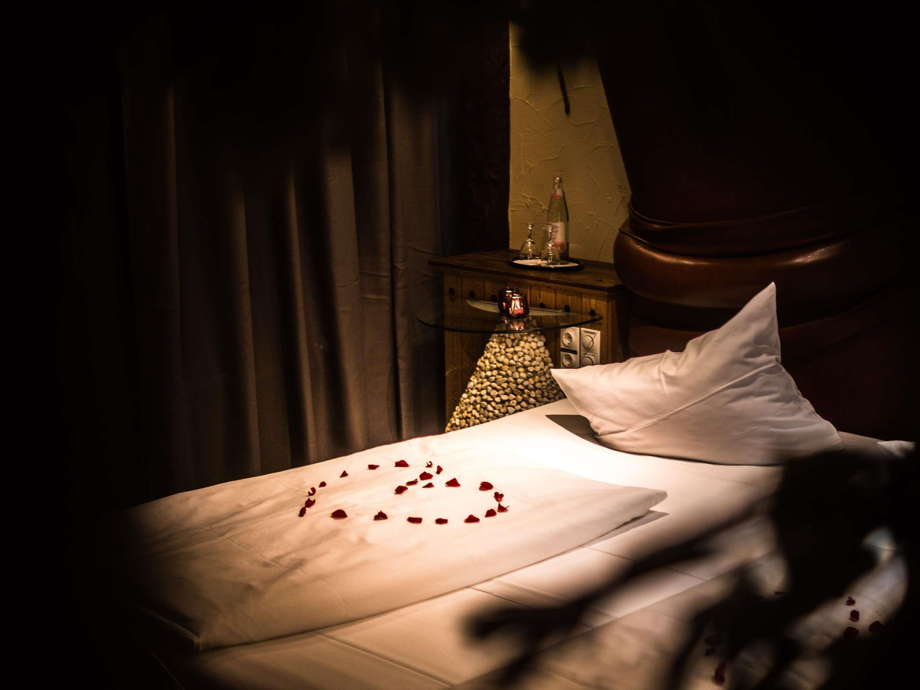 Una habitación tenuemente iluminada con una cama, una mesita de noche con una botella y una lámpara.
