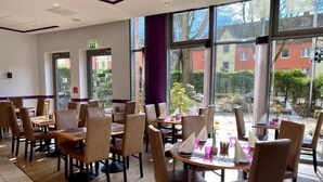Un restaurante con mesas, sillas, ventanas amplias y vistas al exterior.