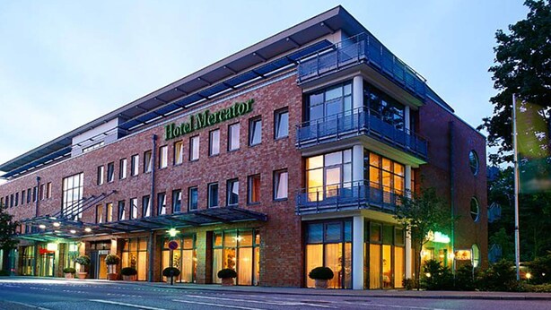 Un hotel con fachada de ladrillo moderno, amplias ventanas y zona de acceso cubierta.