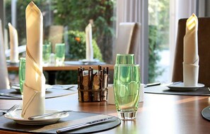Una mesa de comedor dispuesta con servilletas dobladas, una copa y un cuchillo sobre un mantel individual.