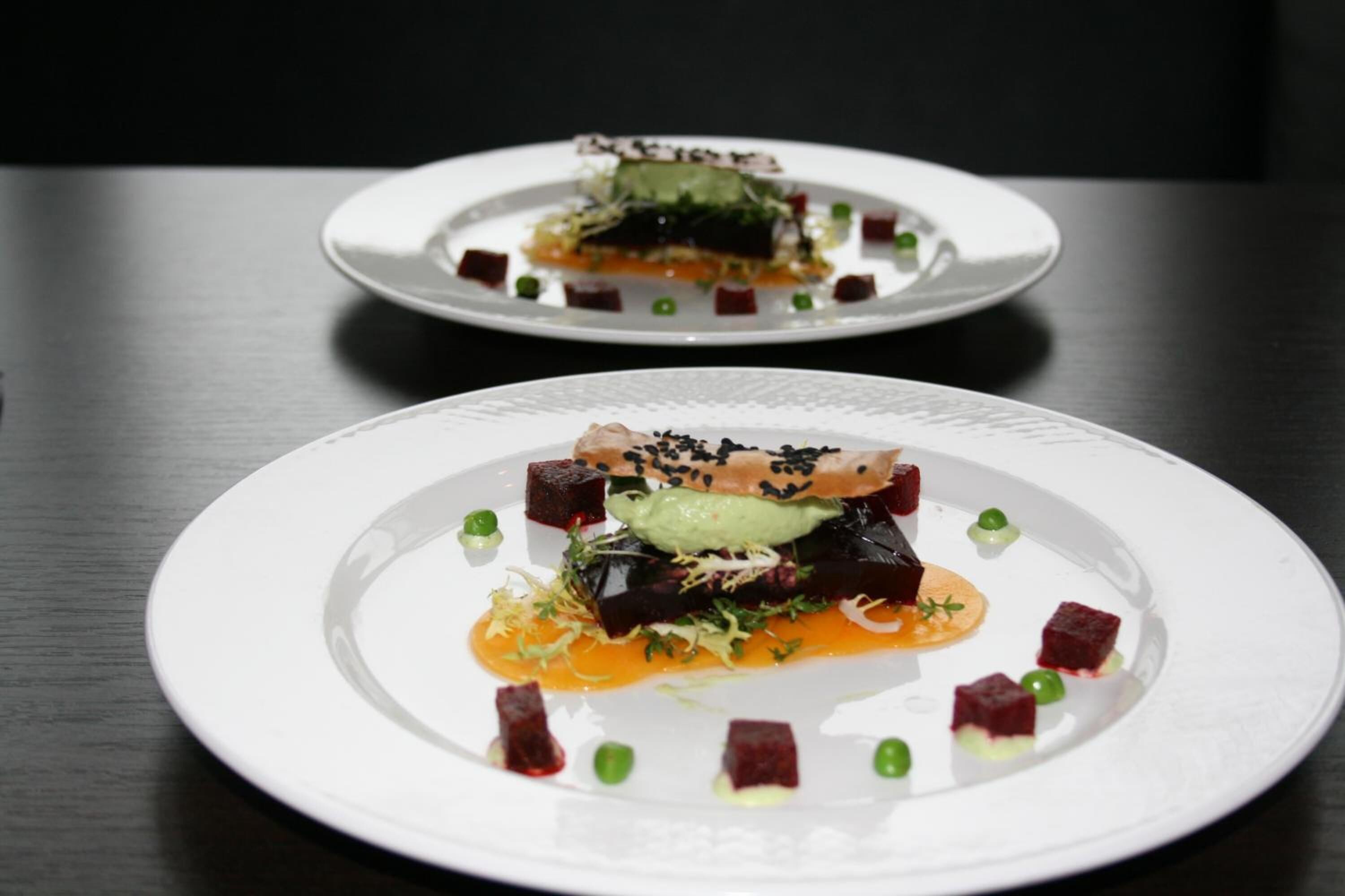 Deux assiettes blanches contenant de la nourriture, posées sur une table sombre.
