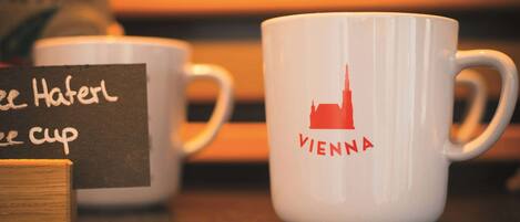 Two white mugs with "Vienna" and "coffee cup" labels, placed on a table with a wooden block and a blackboard sign.