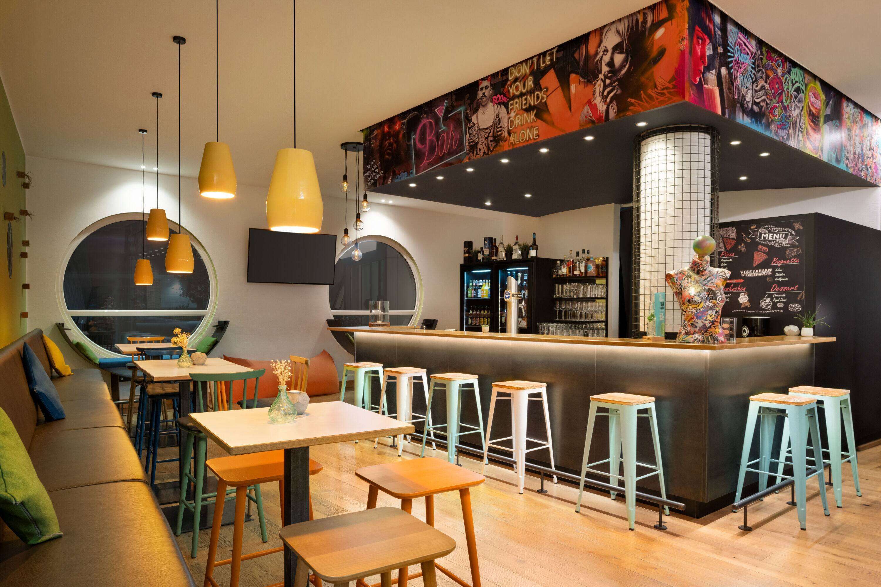 A bar area with stools, a counter, and a mural.