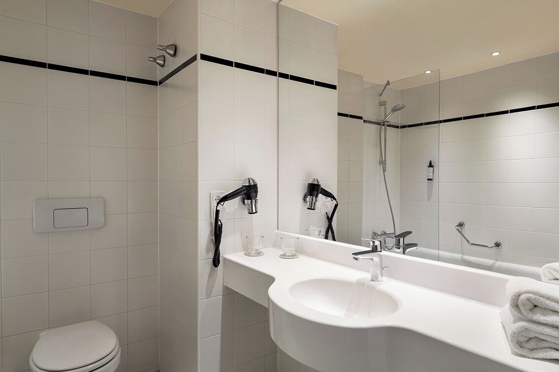 A modern bathroom with a white sink, mirror, and shower.