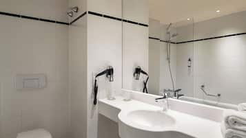 Un baño moderno con lavamanos, espejo y ducha blancos.