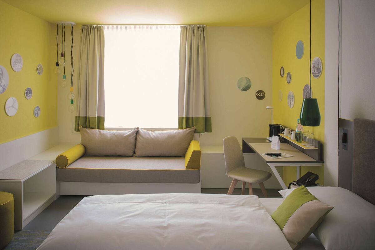A hotel room with a bed, a desk, and a sofa.