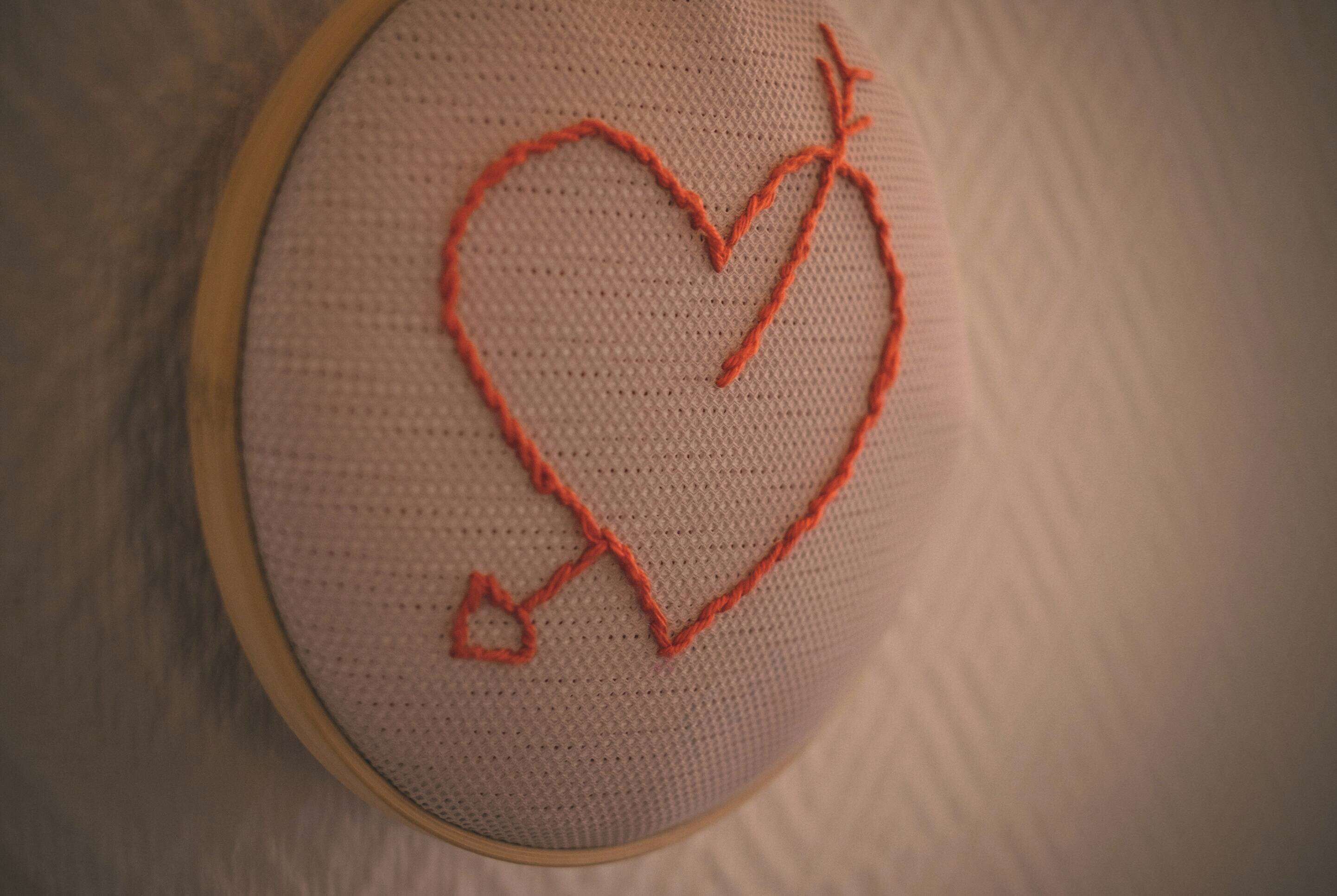 Primer plano de un bordado con forma de corazón sobre una superficie textil.