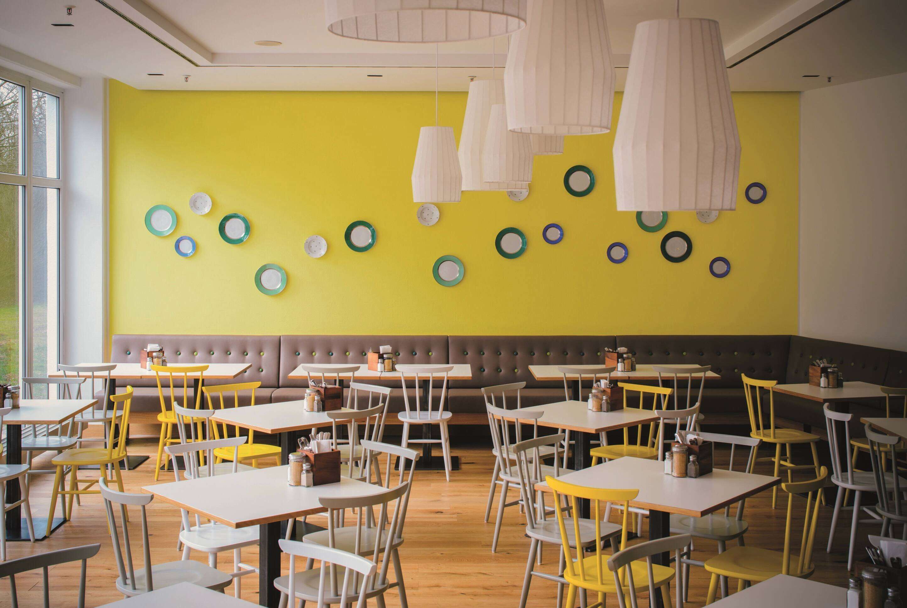 A restaurant interior with yellow walls, wooden tables, and chairs.