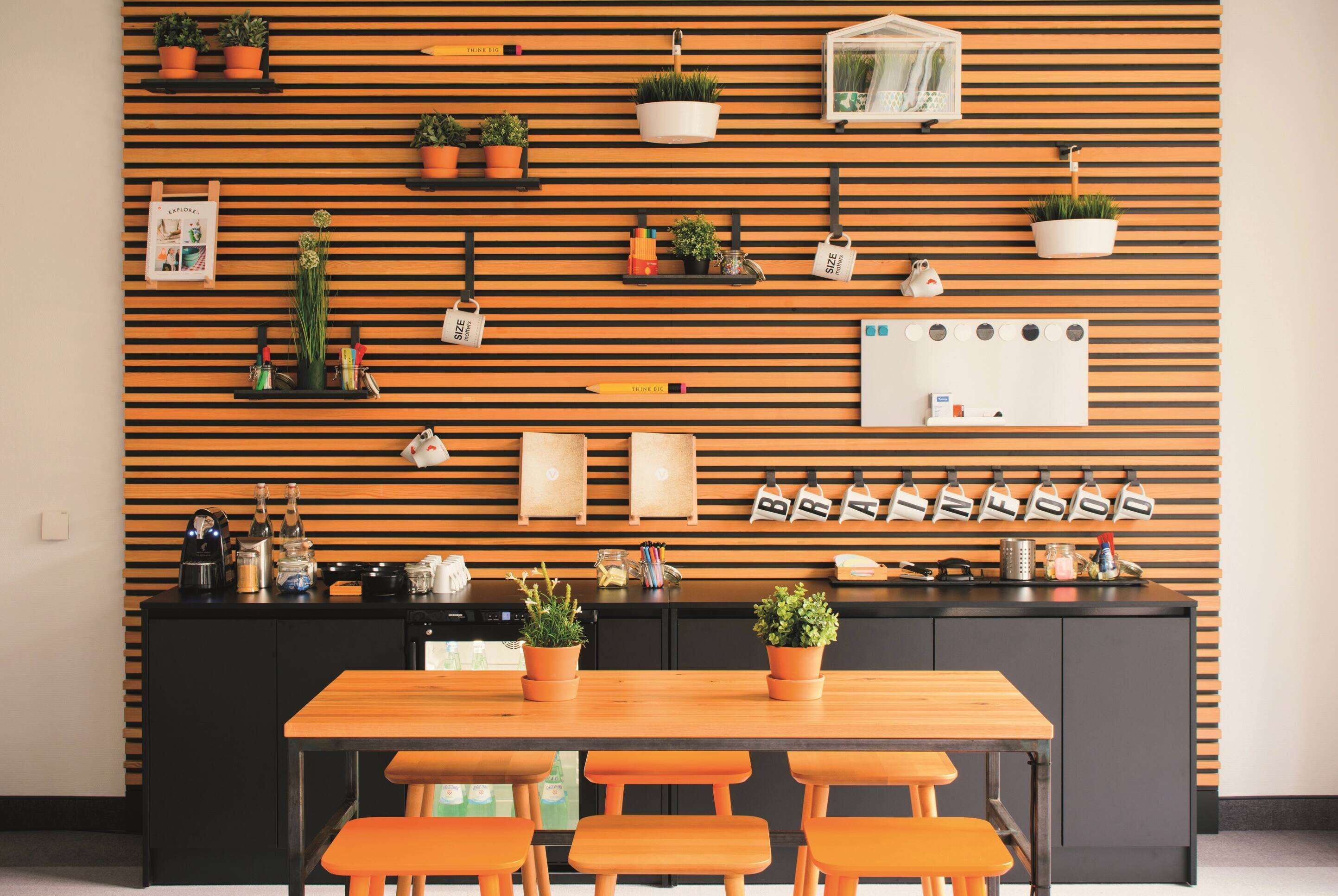 Una cocina moderna con listones de madera, plantas en macetas y una encimera negra.