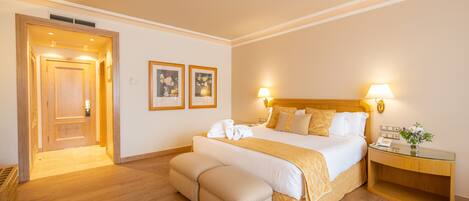 A hotel room with a large bed, bedside lamps, a wooden nightstand, and a bench.