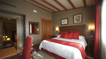 Een hotelkamer met een groot bed, een houten hoofdeinde, een bureau met stoel en een spiegel.