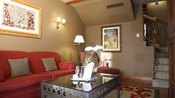 A living room with a red sofa, a glass coffee table, and a staircase.