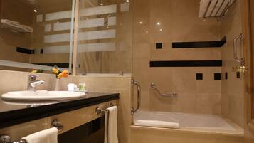 A modern bathroom with a sink, mirror, and bathtub.