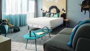 Una habitación de hotel moderna con una cama grande, un sofá, un escritorio y una silla.