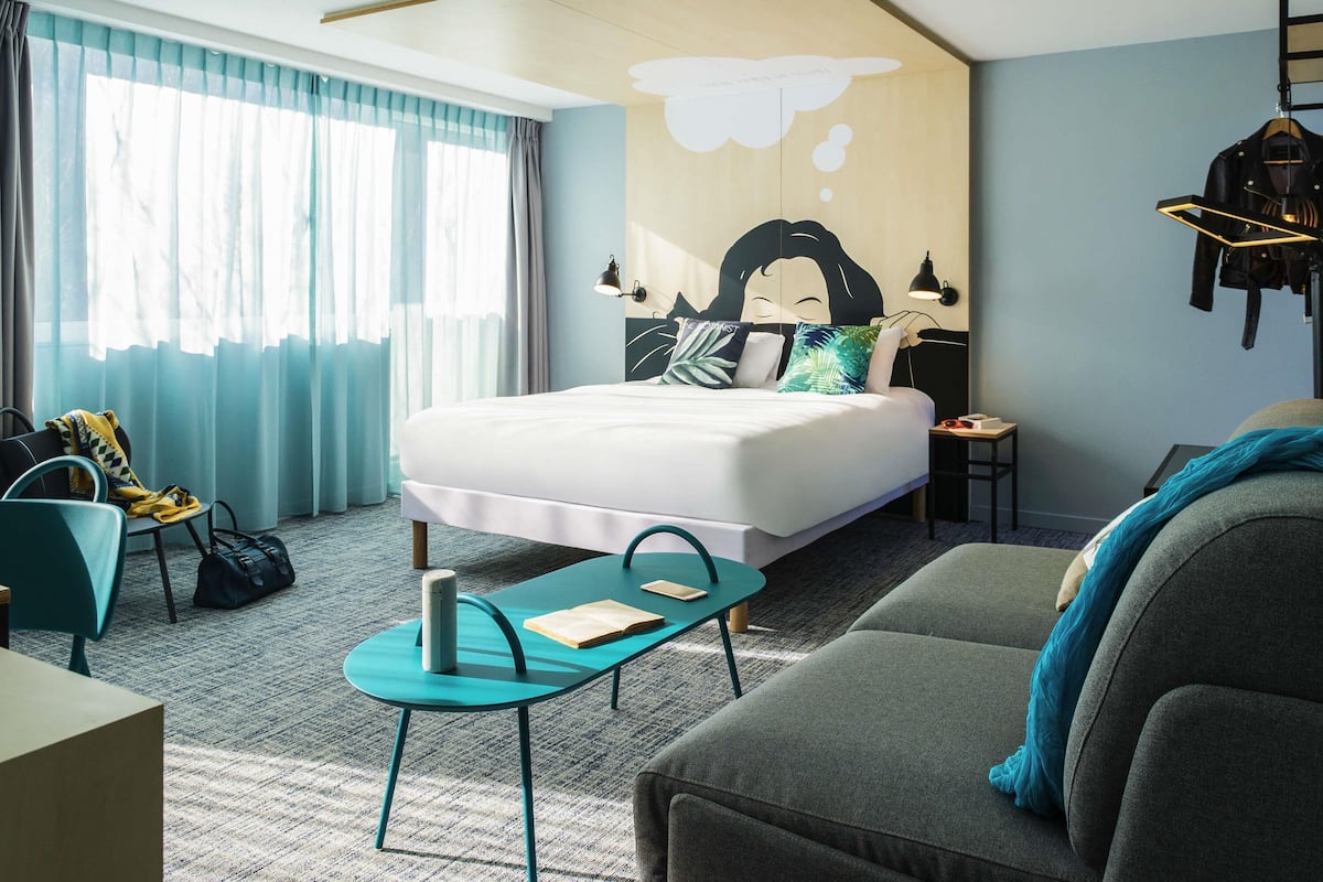 Ein modernes Hotelzimmer mit einem großen Bett, einer Couch, einem Schreibtisch und einem Stuhl.