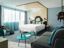 Una habitación de hotel moderna con una cama grande, un sofá, un escritorio y una silla.