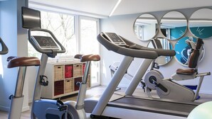 Un gimnasio con bicicletas estáticas, una cinta de correr y pelotas de ejercicios.
