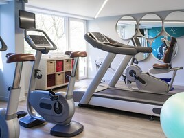 Un gimnasio con bicicletas estáticas, una cinta de correr y pelotas de ejercicios.