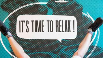 A person lying on a circular platform with a speech bubble saying "IT'S TIME TO RELAX!".