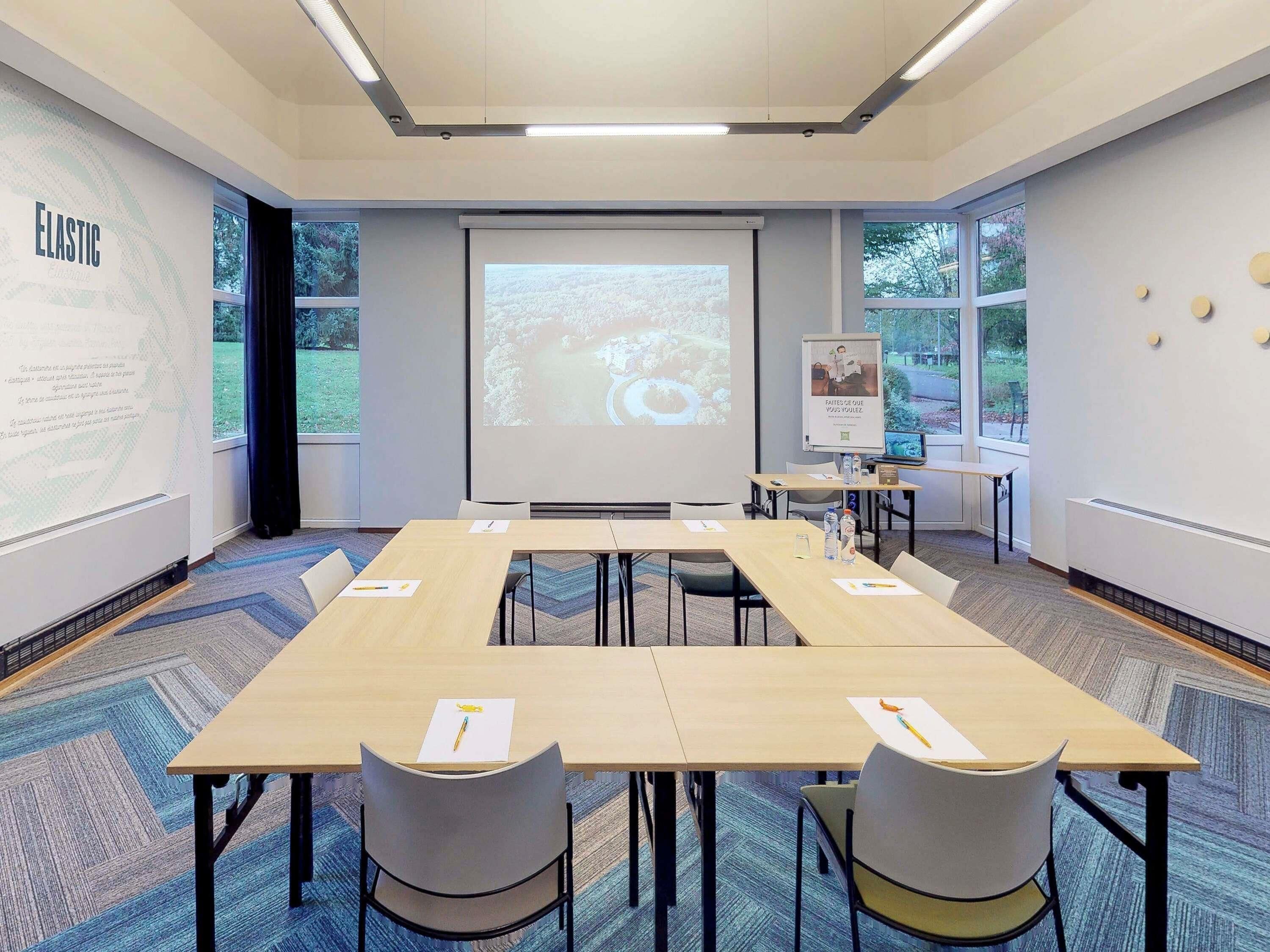 A conference room with a large screen, projection screen, and presentation board.
