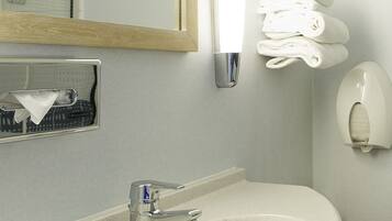 A bathroom with a sink, mirror, towel rack, and hand dryer.